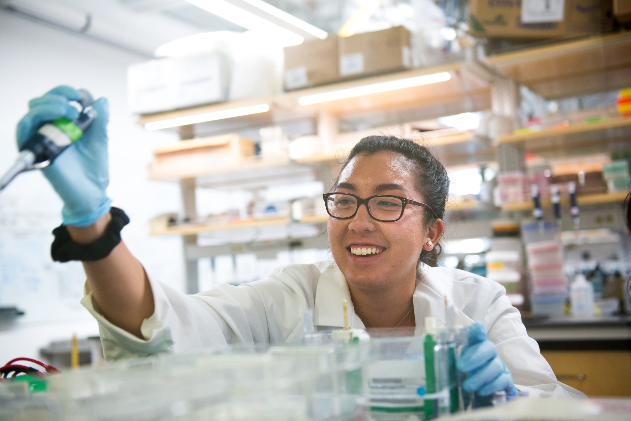 A scientist in a white coat works in a lab